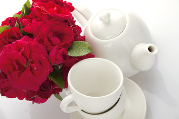 White crockery for tea and a bouquet of roses