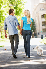 Couple walking with dog in city street