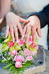 Hands and rings on wedding bouquet