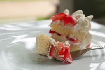 A piece of homemade strawberry cake with cream on fork
