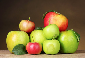 Many fresh organic apples on wooden table on yellow background