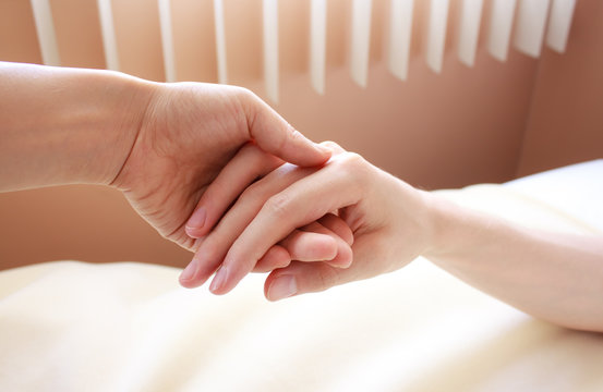 Holding hand of a sick loved one in hospital bed