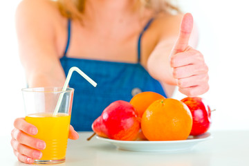 Girl  sitting at table and giving orange juice. Close up