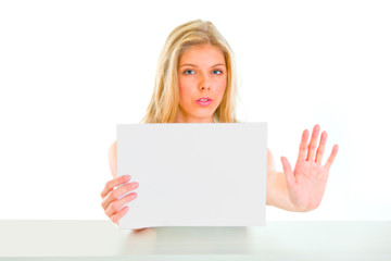 Naklejka premium Concerned girl holding blank paper and showing stop gesture