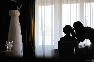 Silhouettes of a bride applying make-up and a make-up artist - obrazy, fototapety, plakaty