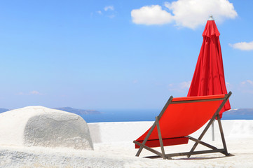 roter Liegestuhl vor Meer und blauem Himmel