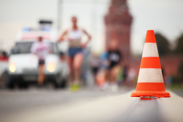 Close-up view of color cone on road on background of running man