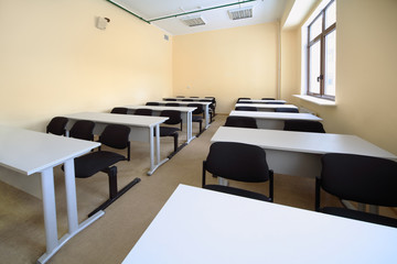 Empty beige classroom with wooden school desks