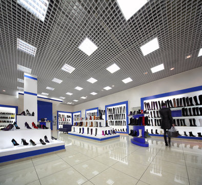 Inside spacious lighting shoes shop with models on white shelves