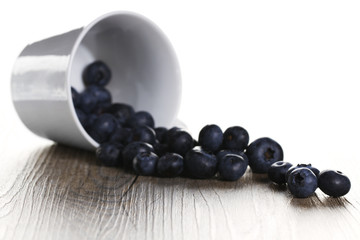 blaubeeren rollen aus umgekippter tasse mit gegenlicht