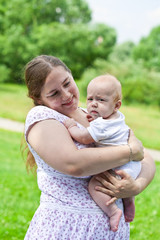 Fototapeta premium Young mum walks with the child in city park