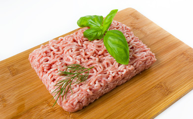 minced meat with basil on a wooded cutting board