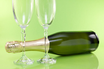 champagne bottle and glasses on green background.
