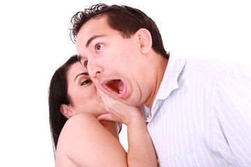 Fototapeta premium Woman tells something into surprised guy's ear isolated on white