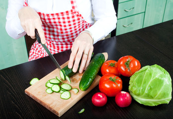 A young woman chops vegetable salad