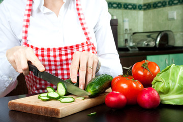 A young woman chops vegetable salad
