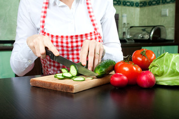 A young woman chops vegetable salad