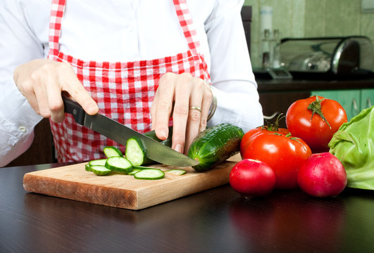 A young woman chops vegetable salad
