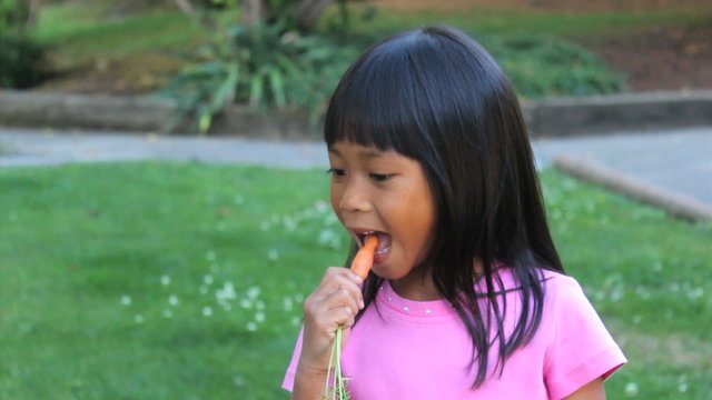 Cute Asian Girl Eating Homegrown Carrot