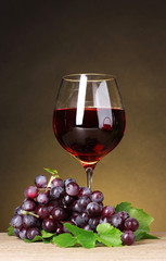 Glass of wine and grapes on yellow background