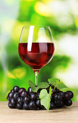 Ripe grapes and  glass of wine on  green background