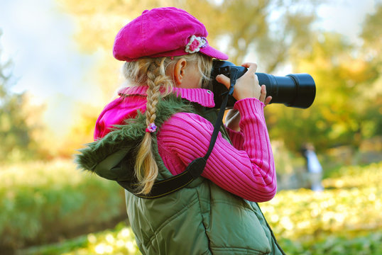 young girl taking photos in autumn park