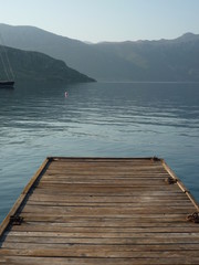 Wooden Pier in calm water with islands and mountains