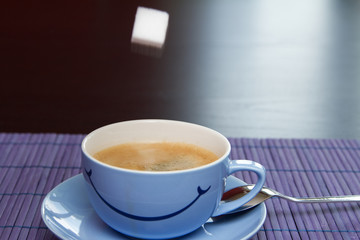 Cup of coffee on the purple table mat