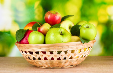 Fresh organic apples in basket on wooden table outside
