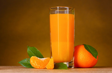 Glass of healthy fresh juice of mandarins on brown background