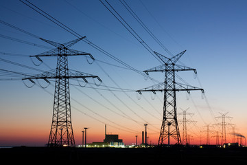 Strommasten in der Abenddämmerung, am Horizont Kernkraftwerk