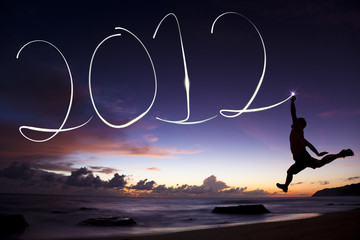 young man jumping and drawing 2012 by flashlight in the air