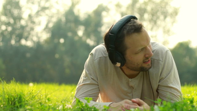 Man with headphones listen to the music on the medow