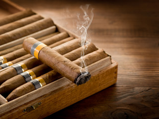 smoking cuban cigar over box  on wood background - obrazy, fototapety, plakaty