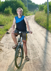 Obraz premium Teenager goes on bicycle on country road