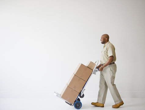 African American deliveryman pushing hand truck with boxes