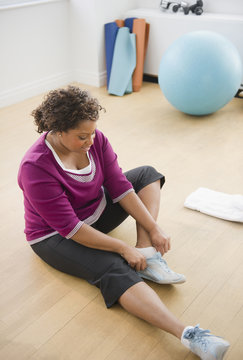African American woman sitting on floor putting on shoes