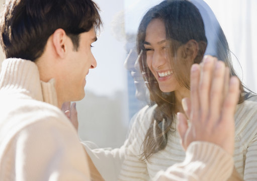 Smiling couple looking through glass at each other