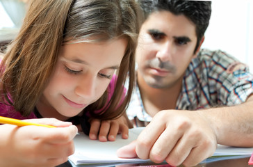 Girl and her young latin father working on a school project