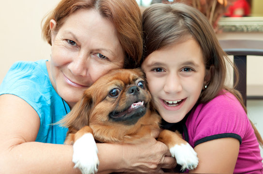 Grandmother And Girl Hugging The Family Dog