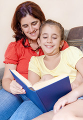 Latin mother and daughter reading a book together