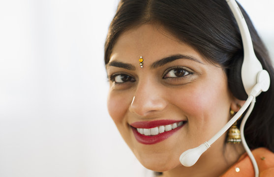 Mixed race woman in traditional Indian clothing talking on headset
