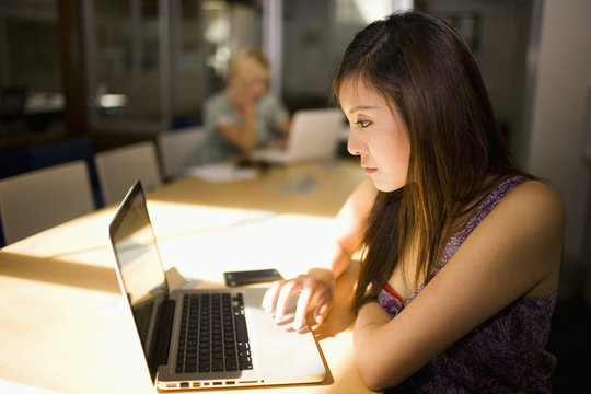 Asian Businesswoman Using Laptop In Communal Workspace