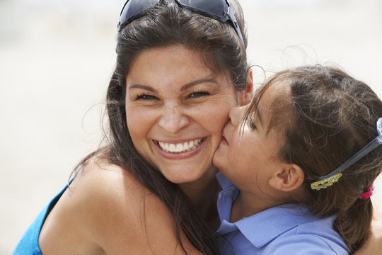 Hispanic daughter kissing smiling mother