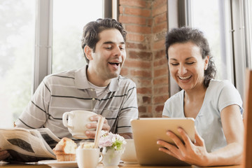 Hispanic couple using digital tablet in cafe