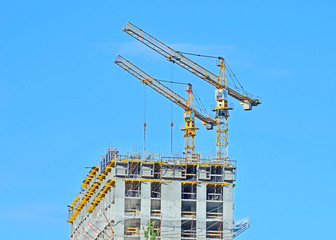 Building crane and building under construction against blue sky