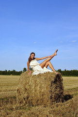 Naklejka na ściany i meble girl in a rural clothing sitting on the haystack