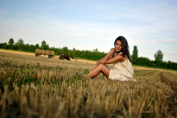 Naklejka na ściany i meble nice girl in national dress sitting on a field in rural areas