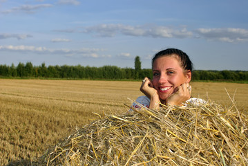 Naklejka na ściany i meble girl in Russian costume lying on a haystack and smiling