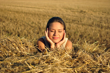 girl in traditional Russian costume resting on a haystack